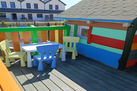 Kleurrijke kinderstoelen en tafel op terras van hut bij «Holiday cottages Sarbinowo», Denemarken.