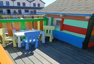 Sedie e tavolo colorati per bambini su terrazza di casetta «Holiday cottages Sarbinowo», Danimarca.
