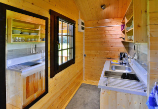 Wood-paneled kitchen in a summer cottage, featuring open shelves, modern sink, and appliances in Denmark.