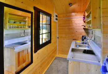 Houten keuken in een zomerhuisje met open planken, moderne spoelbak en apparatuur in Denemarken.
