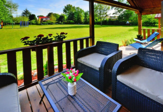 Træterrasse med komfortable havemøbler og udsigt til stor grøn have ved sommerhytter i Ustronie Morskie.