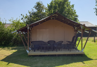 Een safaritent met plastic stoelen op een houten veranda bij Camping de Noorde in Overijssel, Nederland.