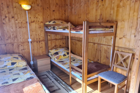 Houten kamer met stapelbed, eenpersoonsbed, stoel en nachtkastje bij Jarosławiec huisjes in Denemarken.
