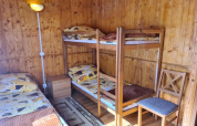 Holzverkleidetes Zimmer mit Etagenbett, Einzelbett, Stuhl und Nachttisch in Jarosławiec Hütten, Dänemark.