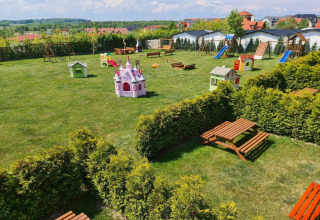 Playground with slides, swings, playhouses, and picnic tables at Single-storey cottages Jarosławiec, Denmark.