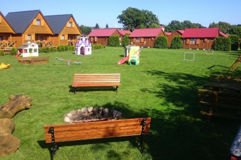 Speelplaats en vuurplaats voor houten huisjes bij Single-storey cottages Jarosławiec in Denemarken.