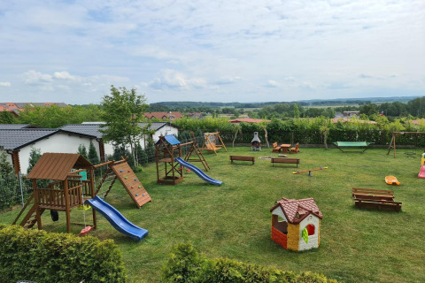 Speeltuin bij gelijkvloerse huisjes Jarosławiec met glijbanen, schommels en bankjes op een grasveld.