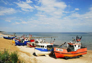 Kleurige vissersboten liggen op het zandstrand bij een blauwe lucht in Jarosławiec, Denemarken.