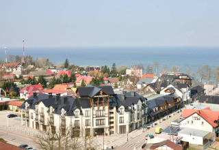 View of a seaside town with colorful rooftops and modern buildings near the sea, taken from above.