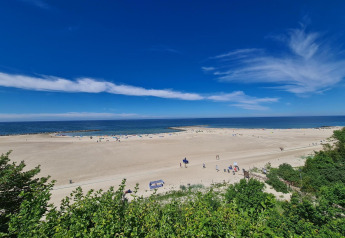 Bred sandstrand med blå himmel og havudsigt set fra Single-storey cottages Jarosławiec, Danmark.