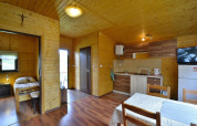 Interior de la cabaña Holiday cottage Rusinowo con paredes de madera, dormitorio, cocina y mesa comedor.