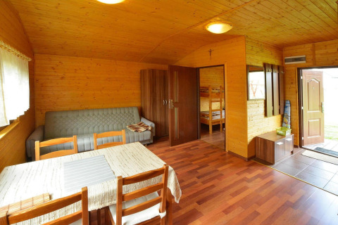 Indvendig udsigt af Holiday cottage Rusinowo med træmøbler, sofa og adgang til soveværelse.