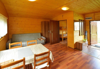 Vista interior de Holiday cottage Rusinowo con muebles de madera, sofá y acceso al dormitorio.
