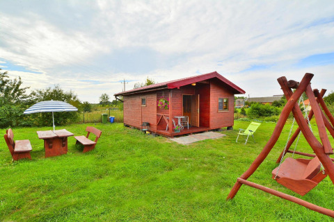 Vakantiehuis Rusinowo in Denemarken met houten hut, schommelbank en tuinset op groene grasveld.