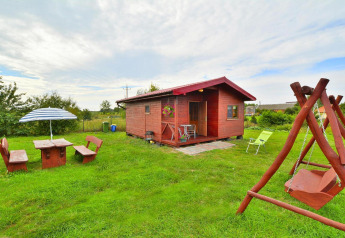 Casa de vacaciones Rusinowo en Dinamarca: cabaña de madera, columpio y zona de picnic en césped verde.