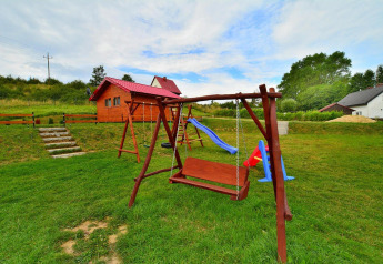 Speelplein met schommel, glijbaan en houten chalet bij vakantiehuis Rusinowo in Denemarken.