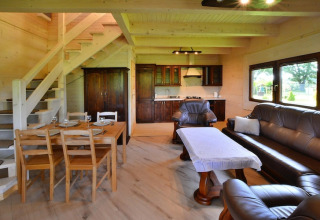 Living and kitchen area in a wooden lodge at Highlander cottages ZUMAR Wicie, with dining table and sofa.