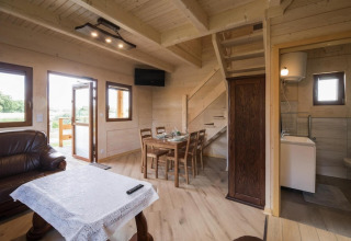 Wooden interior of Highlander cottages ZUMAR Wicie lodge showing dining area, sofa, and bathroom.