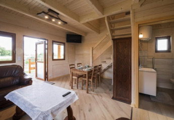 Intérieur en bois du lodge Highlander cottages ZUMAR Wicie avec salle à manger, canapé et salle d’eau.
