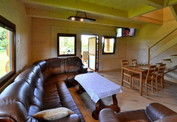 Indvendigt billede af Highlander cottages ZUMAR Wicie i Danmark med lædersofa, spisebord og trappe