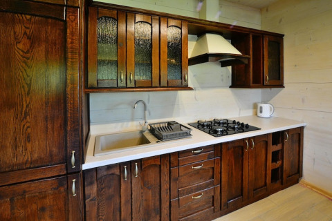 Keuken met donkere houten kasten, spoelbak, gaskookplaat en waterkoker in Highlander cottages ZUMAR Wicie.