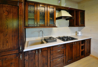 Kitchen with dark wooden cabinets, sink, gas stove and kettle in Highlander cottages ZUMAR Wicie, Denmark.