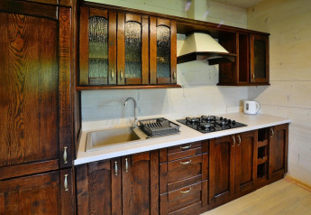 Cocina con armarios de madera oscura, fregadero, estufa a gas y hervidor en Highlander cottages ZUMAR Wicie.