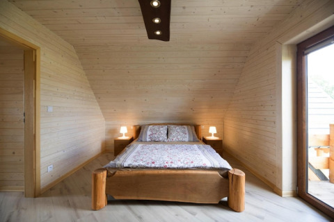Slaapkamer met houten wanden in Highlander cottages ZUMAR Wicie in Denemarken, tweepersoonsbed en lampen.