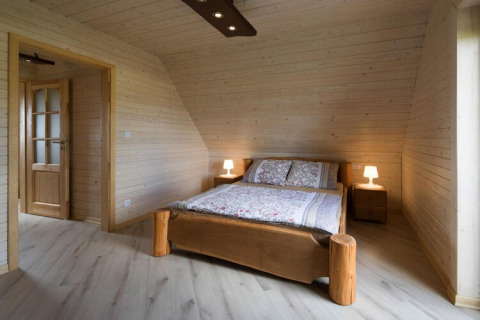 Slaapkamer met houten panelen, tweepersoonsbed en nachtkastjes in Highlander cottages ZUMAR Wicie, Denemarken.