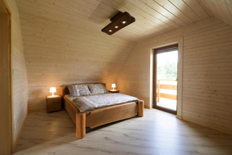 Bedroom in Highlander cottages ZUMAR Wicie, Denmark, featuring wood paneling, double bed, and balcony door.