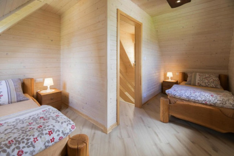 Two cozy bedrooms with wooden walls and single beds at Highlander cottages ZUMAR Wicie, Denmark.