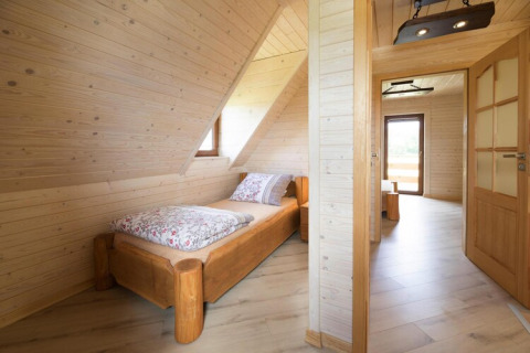 Bright wooden room with a single bed and slanted ceiling at Highlander cottages ZUMAR Wicie, Denmark.