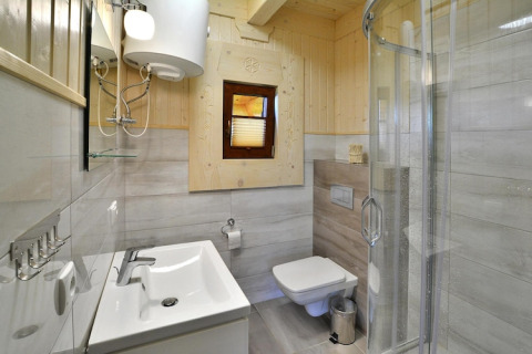 Modern bathroom at Highlander cottages ZUMAR Wicie in Denmark, featuring a glass shower and wood accents.