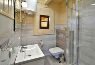 Modern bathroom at Highlander cottages ZUMAR Wicie in Denmark, featuring a glass shower and wood accents.