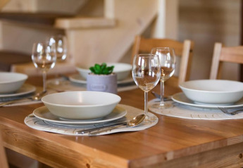 Gedeckter Esstisch mit vier Plätzen in den Highlander cottages ZUMAR Wicie, Dänemark, bereit zum Essen.
