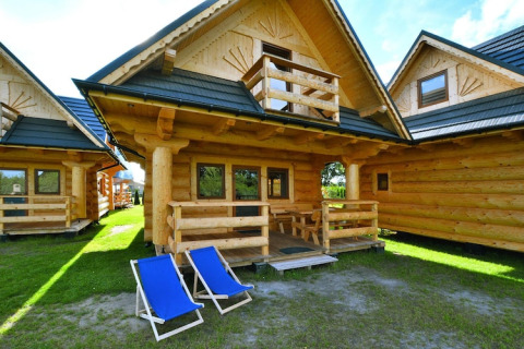 Blokhut van Highlander cottages ZUMAR Wicie in Denemarken, met veranda en twee blauwe ligstoelen buiten.