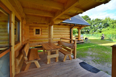 Houten veranda met banken en tafel bij Highlander cottages ZUMAR Wicie in Denemarken op een zonnige dag.