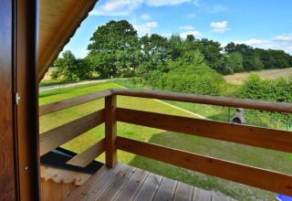 Uitzicht vanaf het houten balkon bij Highlander cottages ZUMAR Wicie op groene velden in Denemarken.