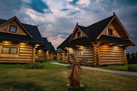 Evening view of cozy log cabins at Highlander cottages ZUMAR Wicie with warm lights, located in Denmark.