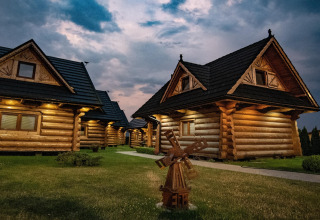 Sfeervol avondbeeld van houten chalets bij Highlander cottages ZUMAR Wicie met verlichting in Denemarken.