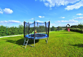 Buitenspeeltuin met trampoline en glijbaan bij Highlander cottages ZUMAR Wicie op een zonnige dag in Denemarken.
