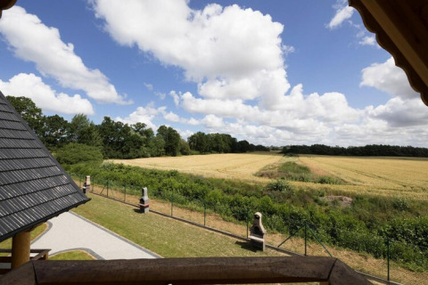View from Highlander cottages ZUMAR Wicie in Denmark, showing fields, trees, and a blue sky with clouds.