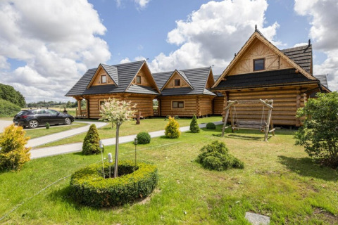 Blokhutten met zwart dak, groene tuin en schommel bij Highlander cottages ZUMAR Wicie in Denemarken.