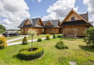 Blokhutten met zwart dak, groene tuin en schommel bij Highlander cottages ZUMAR Wicie in Denemarken.