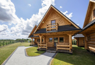 Blokhutten bij Highlander cottages ZUMAR Wicie in Denemarken, omgeven door groen en blauwe lucht.