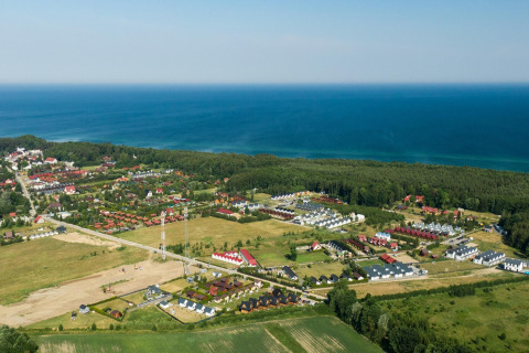 Luchtfoto van Highlander cottages ZUMAR Wicie nabij de kust, omgeven door velden en zee in Denemarken.
