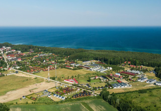 Aerial view of Highlander cottages ZUMAR Wicie near the coastline, surrounded by fields and sea in Denmark.