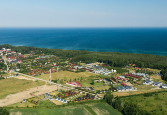 Luchtfoto van Highlander cottages ZUMAR Wicie nabij de kust, omgeven door velden en zee in Denemarken.