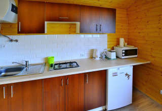 Cabin kitchen at Domki letniskowe Rusinowo in Denmark with stove, sink, microwave, and mini fridge.