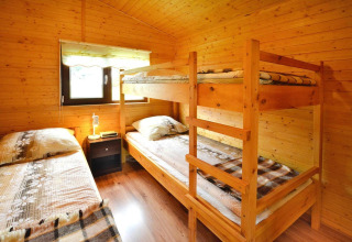 Cozy wooden bedroom with a bunk bed, single bed, and window at Domki letniskowe Rusinowo in Denmark.